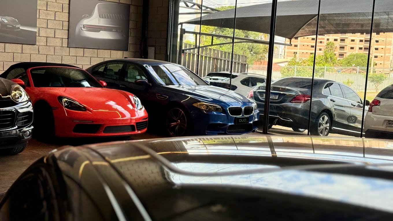 Showroom da DUO MOTORS com Porsche, BMW e Mercedes estacionados lado a lado